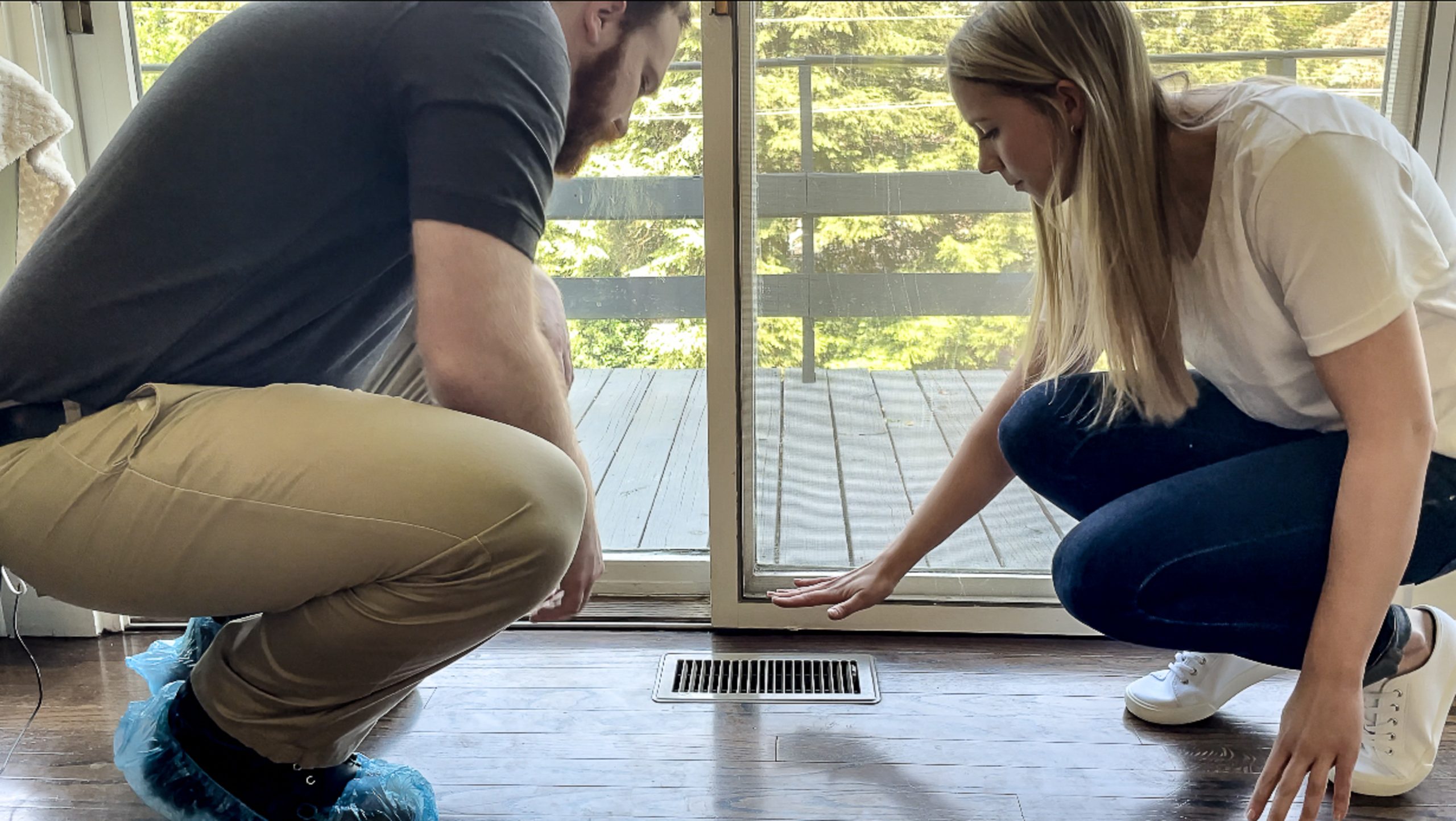 Two people feeling heat coming out of a vent